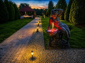 A pathway lined with lights leading to a gazebo and a statue.