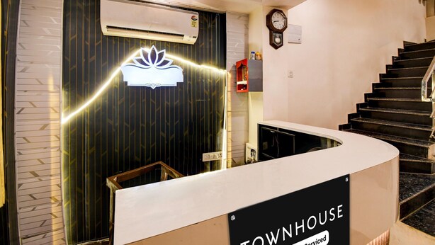 En receptionsdisk med en skylt där det står ”TOWNHOUSE”, en klocka på väggen och en trappa som leder upp till en våning ovanför.