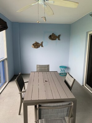 Ein Zimmer mit Tisch, Stühlen, einem Deckenventilator und zwei Wandbildern.