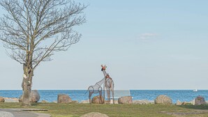 Una escultura de jirafas cerca de un banco frente al mar.