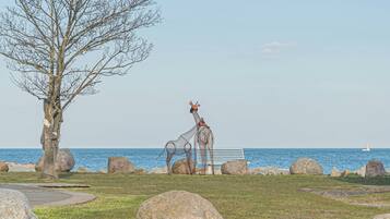 Eine Skulptur von Giraffen in der Nähe einer Bank am Meer.