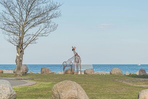 Una escultura de jirafas cerca de un banco frente al mar.