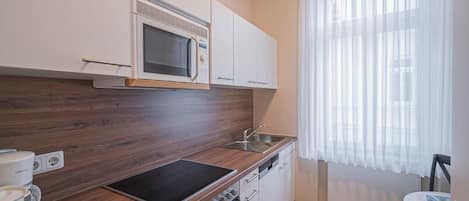Una cocina compacta con microondas, estufa y lavamanos.