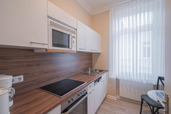 A compact kitchen with a microwave, stove, and sink.