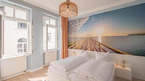 Un dormitorio con cama, mesita de noche, lámpara colgante y un amplio ventanal.