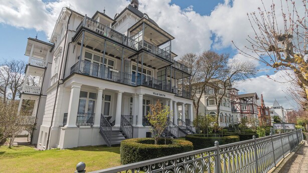 Un edificio de varios pisos con balcones, una escalera y un césped bien cuidado.