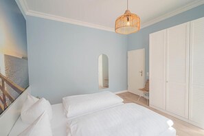 A bedroom with a bed, a hanging light fixture, a wardrobe, and a mirror.