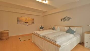 A bedroom with a bed, bedside tables, a lamp, a wall art piece, and a floor mat.