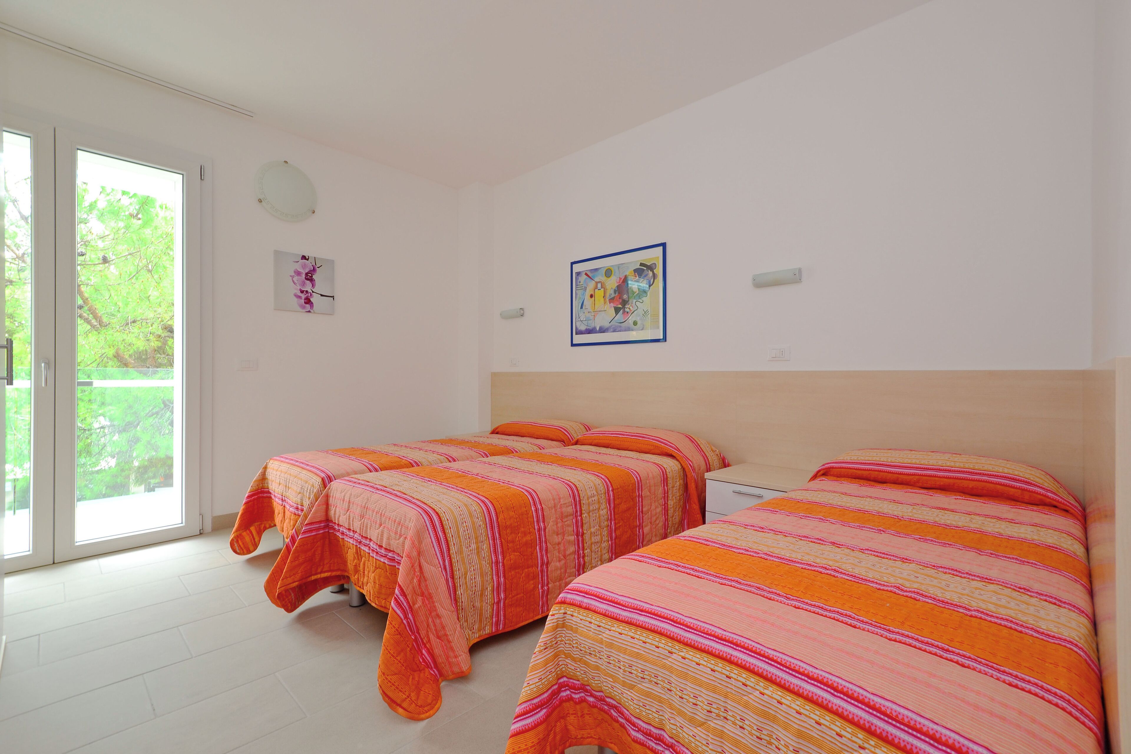 A room with two beds, a large window, and a door leading outside.