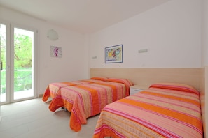 A room with two beds, a large window, and a door leading outside. - Inviting Seven Guests Apartment Near the Beach (Lignano Sabbiadoro)