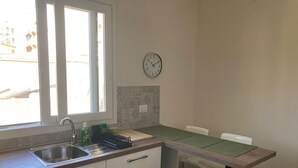 A kitchen with a window, sink, countertop, and a clock on the wall. - Newly renovated house, bright and within walking distance of Ortigia and the Greek theater. (Siracusa)