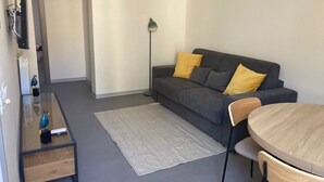 A modern living room with a grey sofa, a wooden coffee table, a floor lamp, and a round wooden table. - Newly renovated house, bright and within walking distance of Ortigia and the Greek theater. (Siracusa)
