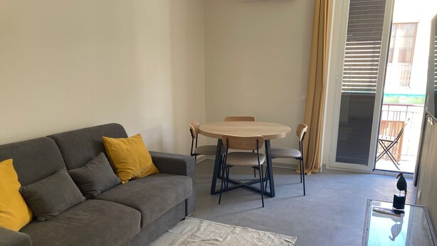 A living room with a grey sofa, yellow cushions, a round wooden table, and a glass coffee table. - Newly renovated house, bright and within walking distance of Ortigia and the Greek theater. (Siracusa)