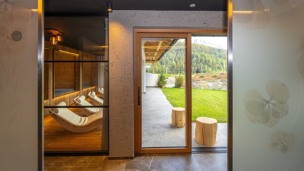 A modern interior with a hammock, a glass door leading outside, and a view of a green landscape. - Apartment 'Altmessnerhof Alpenklee' with Mountain View, Shared Terrace and Wi-Fi (Dobbiaco)