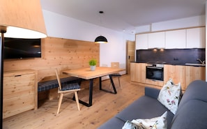 Una cocina moderna con muebles de madera, una mesa de comedor con sillas, un sofá y un televisor.