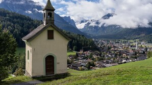 Eine kleine Kirche mit Kirchturm, umgeben von einer Stadt und Bergen.