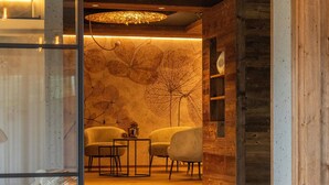 A modern interior with a glass partition, a lounge area with white cushioned chairs, and a dining area with a table and chairs. - Apartment 'Altmessnerhof Steinklee' with Mountain View, Shared Terrace and Wi-Fi (Dobbiaco)