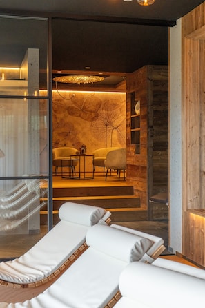 Un intérieur moderne avec une cloison en verre, un coin salon doté de fauteuils blancs et moelleux, et un espace repas avec une table et des chaises.