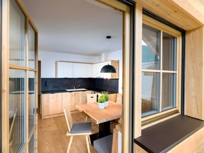Une cuisine moderne avec des meubles en bois, un plan de travail noir et un coin repas comprenant une table et des chaises en bois.