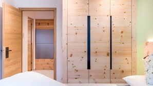 A bedroom with a wooden wardrobe, a bed, and a nightstand.