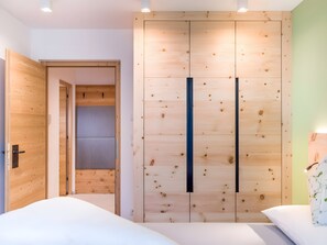 Un dormitorio con un armario de madera, una cama y una mesita de noche.