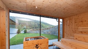 A wooden sauna room with a stone wall, a wooden bench, and a sauna table.
