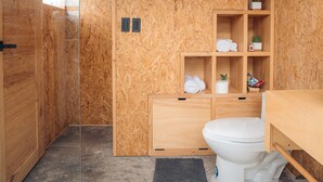 Une petite salle de bain comprenant des toilettes, des étagères et un espace douche.