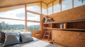 Une pièce avec un lit, une étagère remplie de livres, une échelle et une vue sur l’extérieur.