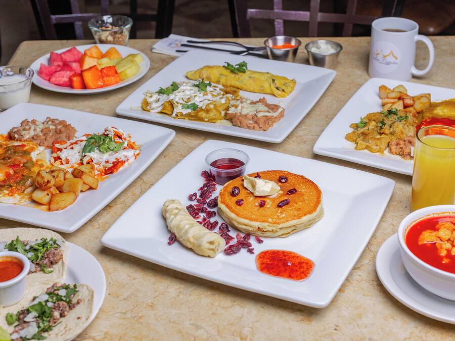 A table with various breakfast dishes including pancakes, omelets, and tacos.