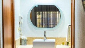 Ein Badezimmer mit einem runden Spiegel, einem weißen Waschbecken und einem Handtuchhalter.