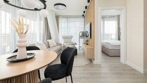 Een moderne woonkamer met een eethoek, een bank, een televisie en een bed op de achtergrond.