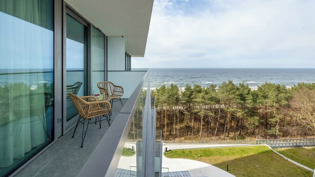 Een balkon met uitzicht op zee en bomen.