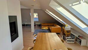 Ein modernes Loft mit Holztisch, integriertem Kamin, gemütlicher Sitzecke und einem Oberlicht.