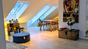Ein Loft-Zimmer mit schrägen Decken, einem Essbereich und einem großen abstrakten Gemälde.