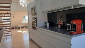 Eine moderne Küche mit integrierten Geräten, einer Kaffeemaschine und Blick auf den Wohnbereich.