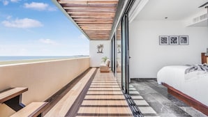A balcony with a wooden ceiling, a bed with a white mattress, and a view of the sea.