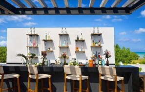 A bar area with wooden chairs and shelves of bottles. - Villa Tiburón Luxury Beach Front Oasis 7/BR (Puerto Morelos)