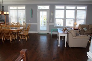A dining area with a round table and chairs, a sofa, and a bench. - Private Pool, Elevator and Canal Front! By Williamson Realty (Ocean Isle Beach)
