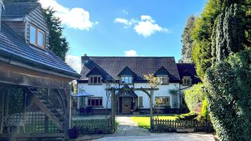 A traditional house with a front porch, a staircase leading to the entrance, and a well-maintained lawn.