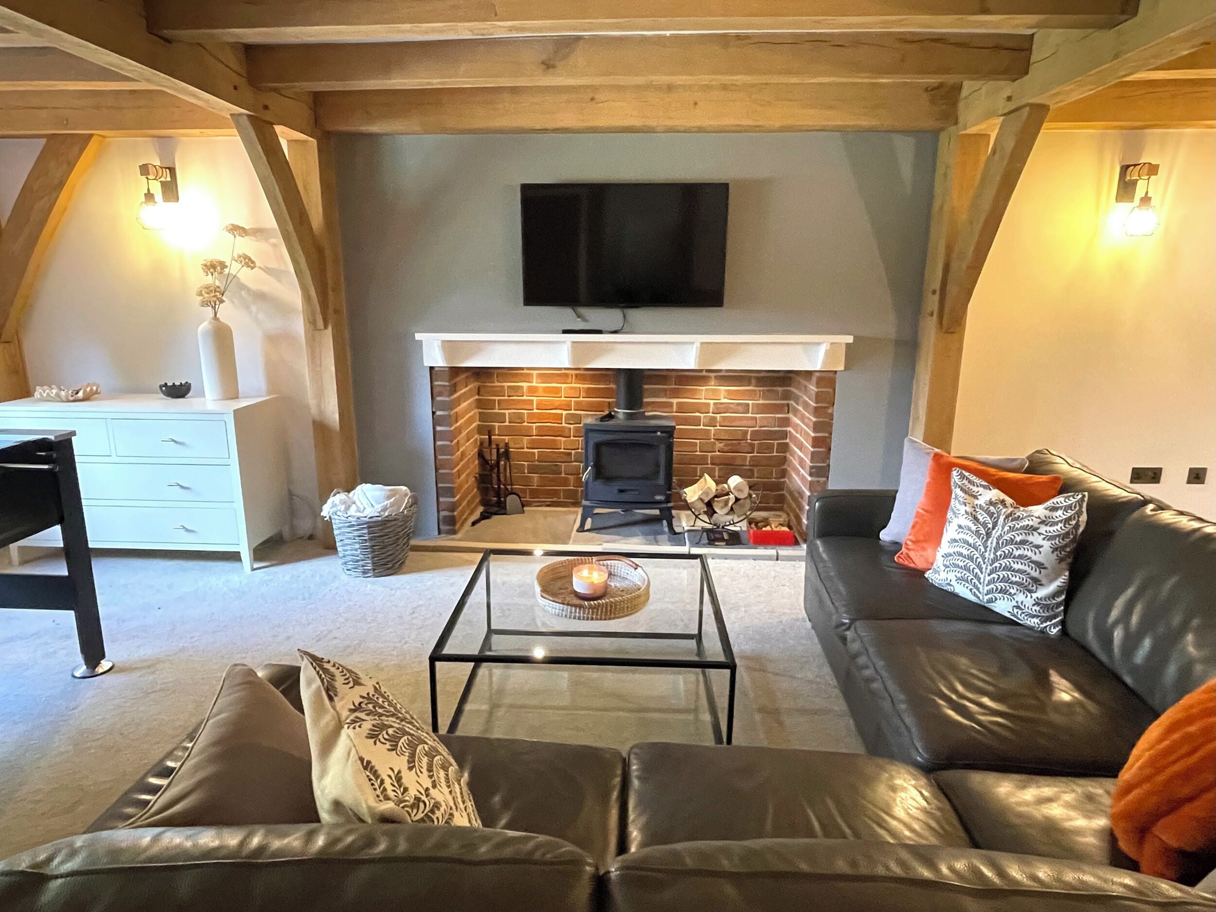 A cozy living room with a fireplace, leather sofa, and a flat-screen TV mounted above the fireplace.