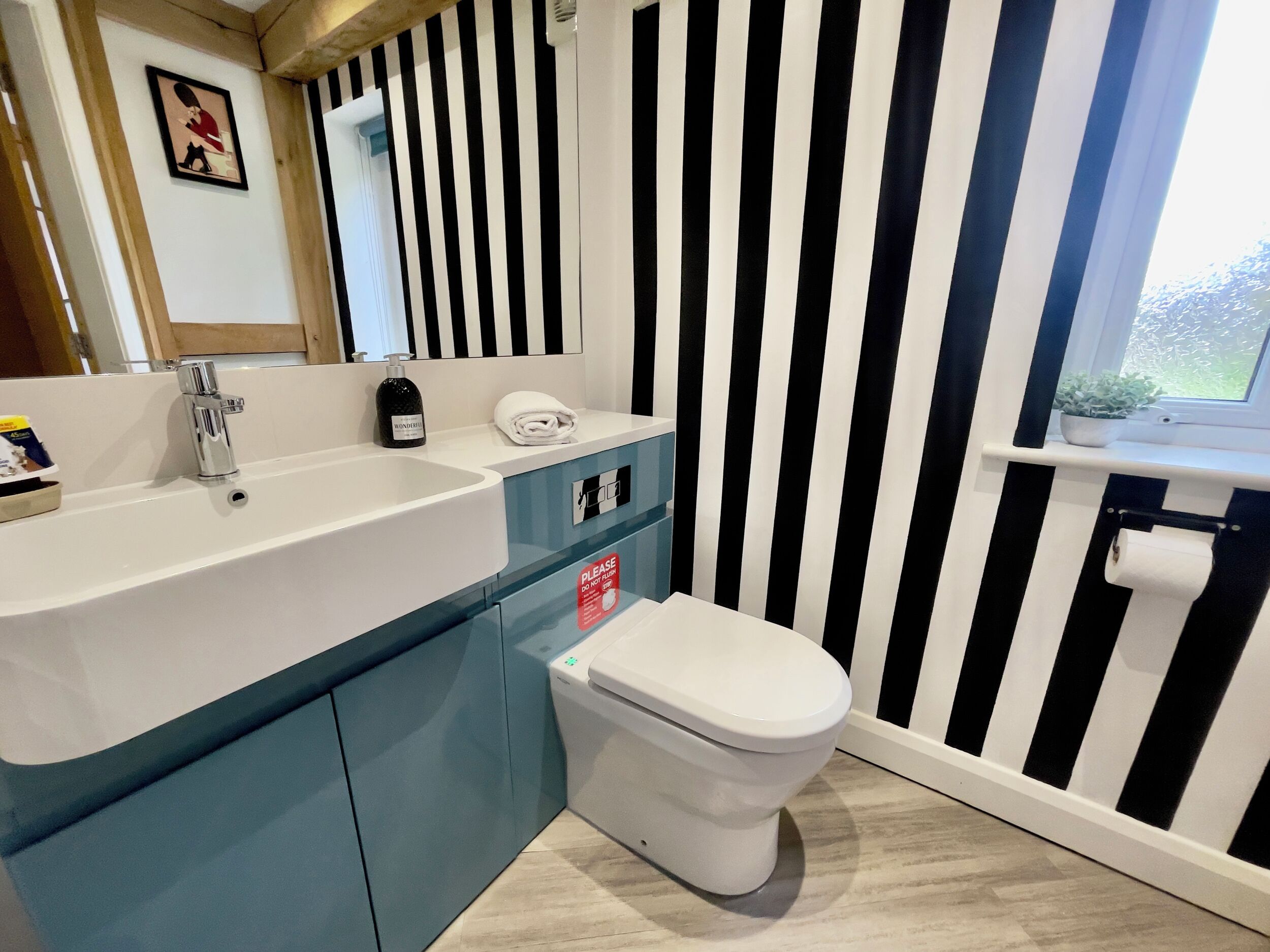 Ein Badezimmer mit Waschbecken, Toilette und einer gestreiften Wand.
