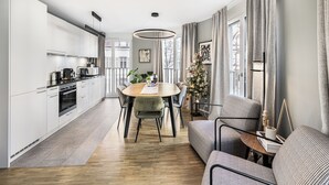 A modern kitchen with white cabinets, a dining table with chairs, a sofa, and a Christmas tree. - Just Sunny – 2.5-Room Apt near Messe & City Center (Basel)