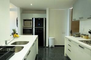 A modern kitchen with stainless steel appliances, a microwave, a refrigerator, a sink, and a trash bin. - Urban Retreat in Reforma + AC + gym (Ciudad de México)
