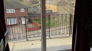 A room with a large sliding glass door leading to a balcony with a metal railing.