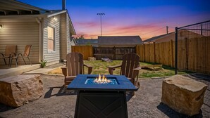 A backyard with a fire pit, outdoor seating, and a wooden fence. - Oak Haus | Group Stay w/ Fenced Yard & Game Room (Windsor)