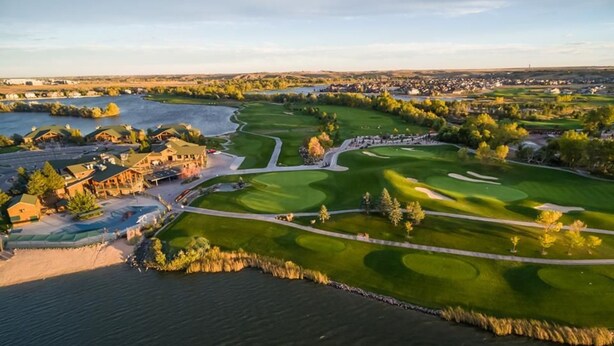 A golf course with a water body, buildings, and a distant town. - Oak Haus | Group Stay w/ Fenced Yard & Game Room (Windsor)