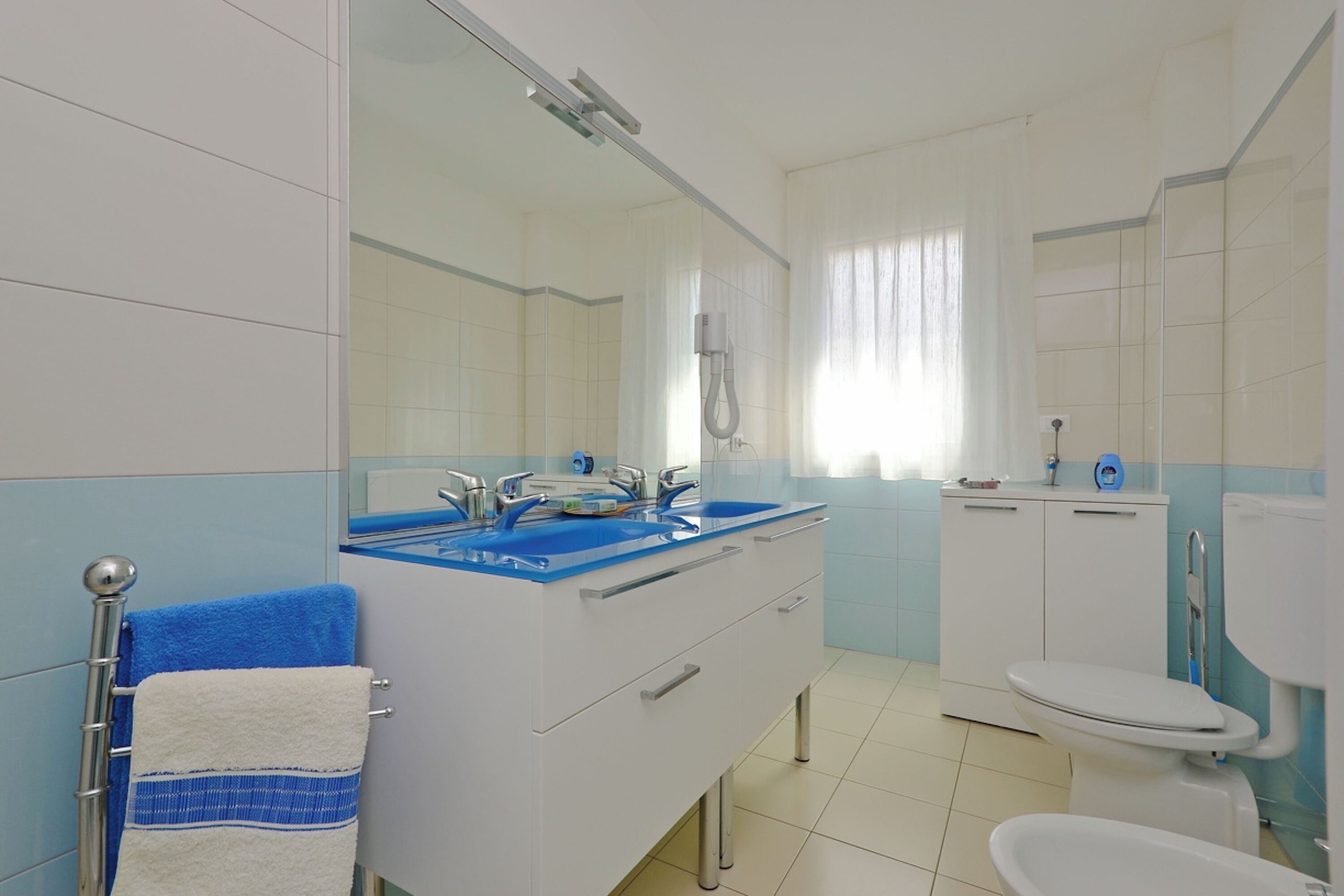 A bathroom with a white sink, blue countertop, and a white toilet.