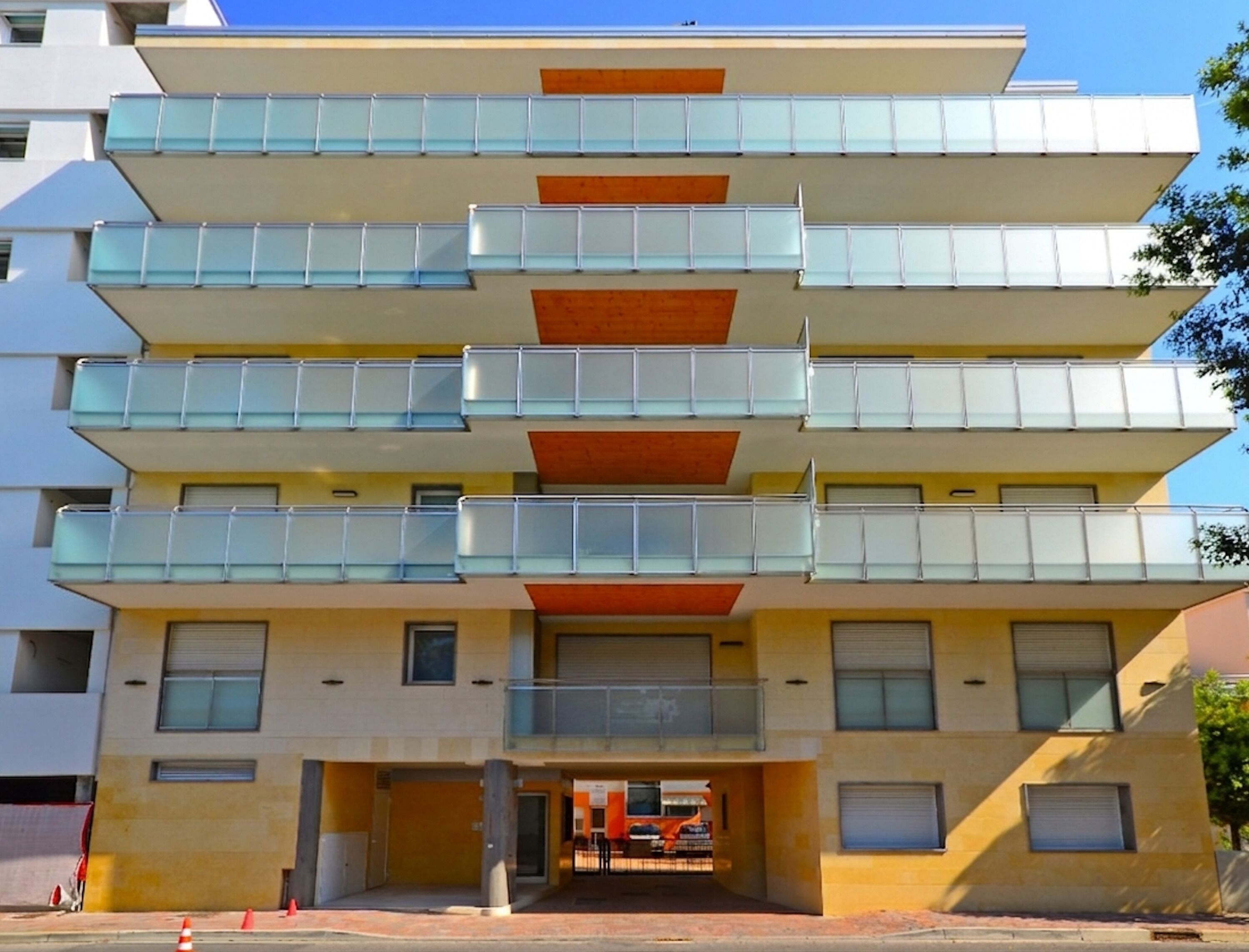 Un edificio a più piani con balconi, un ingresso a livello strada e cielo sereno.