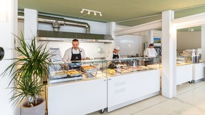 Ein Buffetbereich mit verschiedenen Speisen, einer Topfpflanze und einer modernen Küche im Hintergrund.