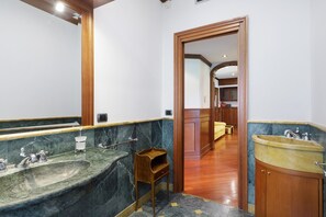 A bathroom with two sinks, a mirror, and a wooden door leading to a hallway. - Suite Somalia Roma Apartment with Balcony, Wi-Fi, and Air Conditioning (Roma)